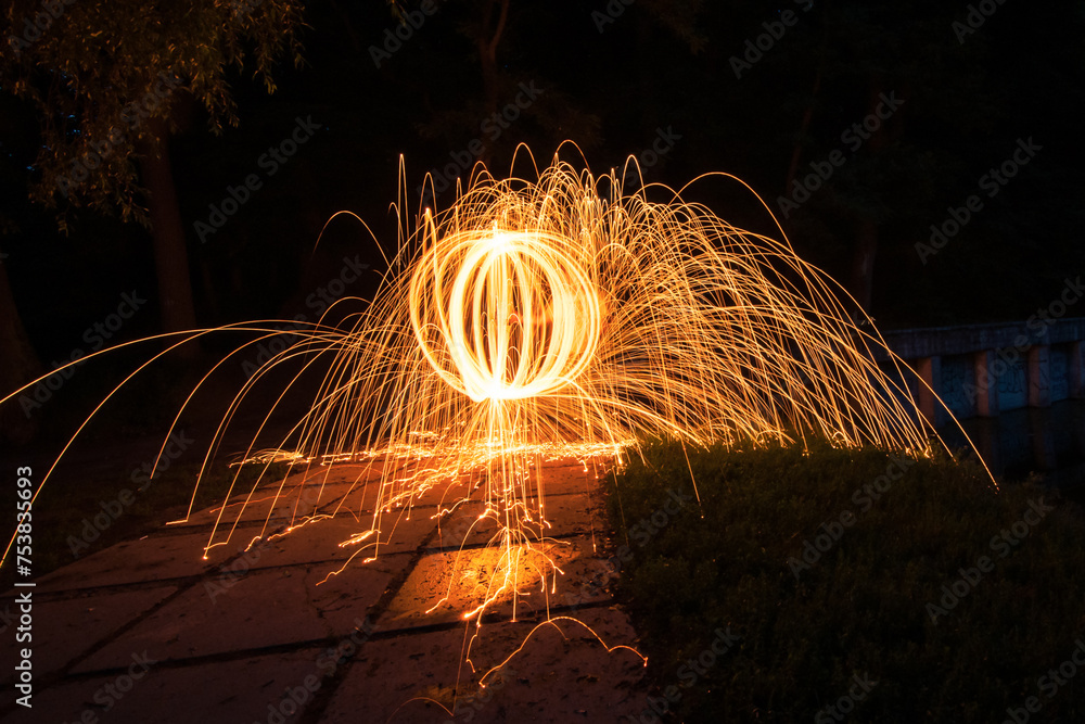 Fireball spinning steel wool in a park. Sparks flying out in all directions due to centrifugal