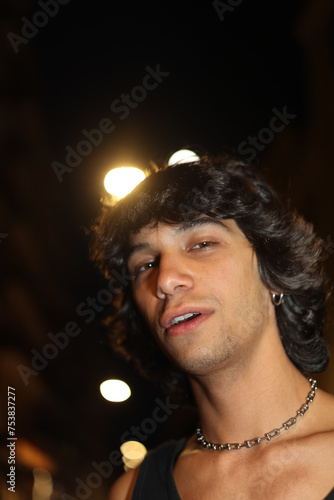 Dazed man with shaggy hair looking at the camera at party outdoors photo