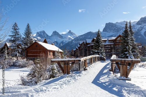 Wooden Pedestrian Footbridge Spring Creek Mountain Village, Canmore Alberta. Distant Snow Covered Three Sisters Canadian Rocky Mountain Peaks Skyline