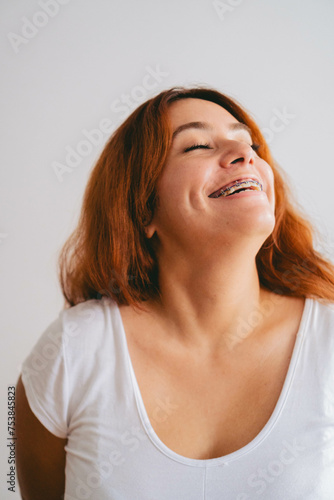 Young latin woman with dyed red hair laughs with closed eyes