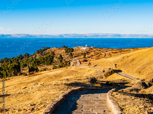 Amazing view of Amantani island at sunset, with cultivated fields and stone path that goes down to the coast, lake Titicaca, Peru 
