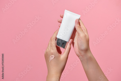 Woman holding makeup tube, testing creamy foundation photo