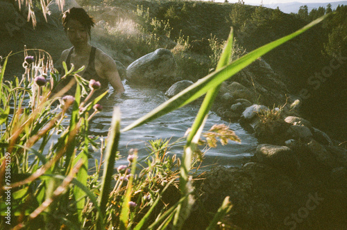 Women enjoying an outdoor hot spring and greenery. photo