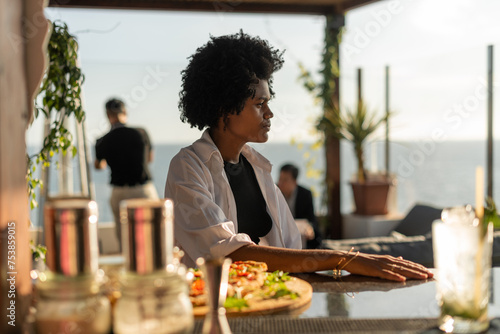 Black woman sitting at the counter in a summer bar photo