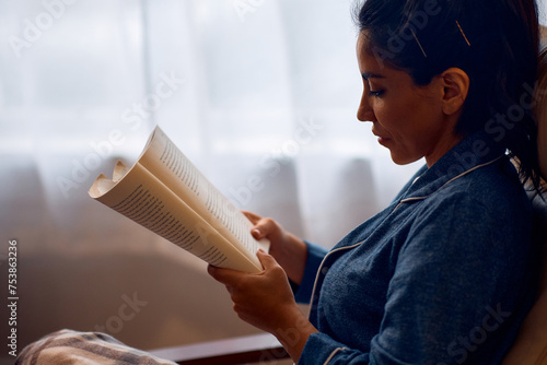 Mid adult woman enjoying in reading  book at home. photo