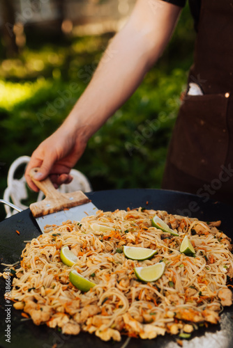Man Preparing Noodle Dish in Outdoor Frying Pan/Stekhäll, 