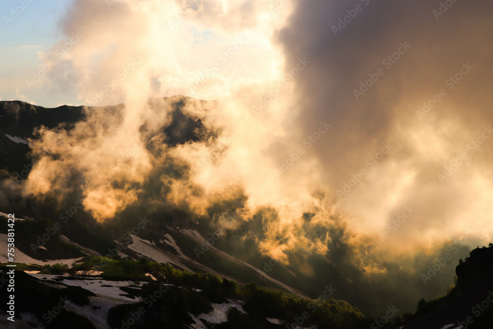 Photo of snowy mountains at sunset. Mountains in the fog.
