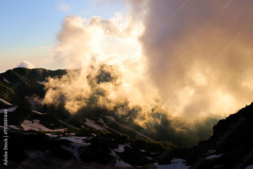 Photo of snowy mountains at sunset. Mountains in the fog.