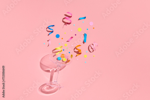 wine glass with confetti on pink background. photo