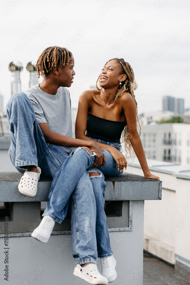 A man and a woman are sitting on the roof of a city building A man and a woman are sitting on the roof of a city building