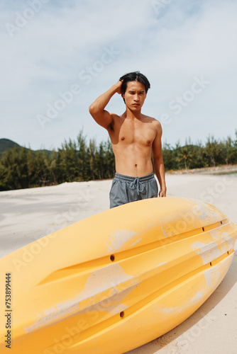 Kayak Fun in the Sun: Active Asian Man Enjoying Water Adventure on Tropical Beach © SHOTPRIME STUDIO