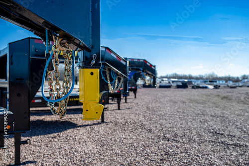 Selective focus on gooseneck trailer hitch with a row of flatbeds lined up. 