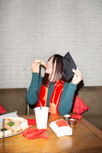 Cheerful Asian female graduate enjoying pizza in cafe photo