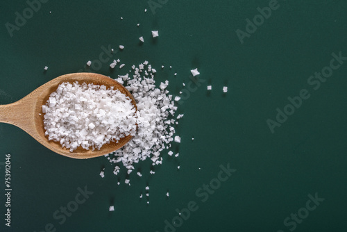 Natural Seasoning: 4K Ultra HD Image of White Salt in Wooden Spoon on Green Background