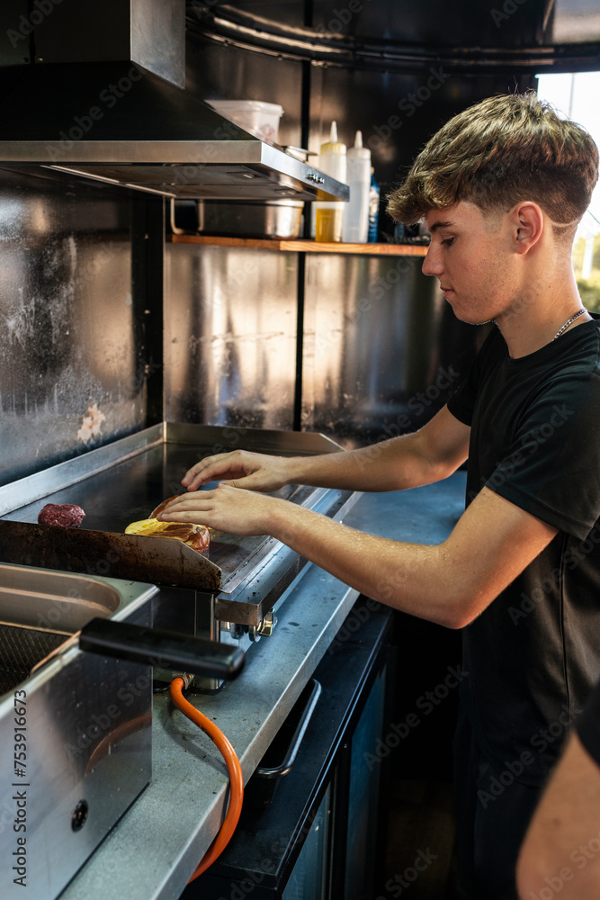 Teen chef cooking cheeseburgers in a food truck Teen chef cooking cheeseburgers in a food truck