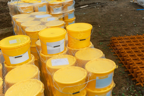 Yellow paint buckets stacked on a construction site. photo