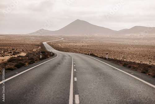 Empty lonely road in desert with sunny and cloudy sky