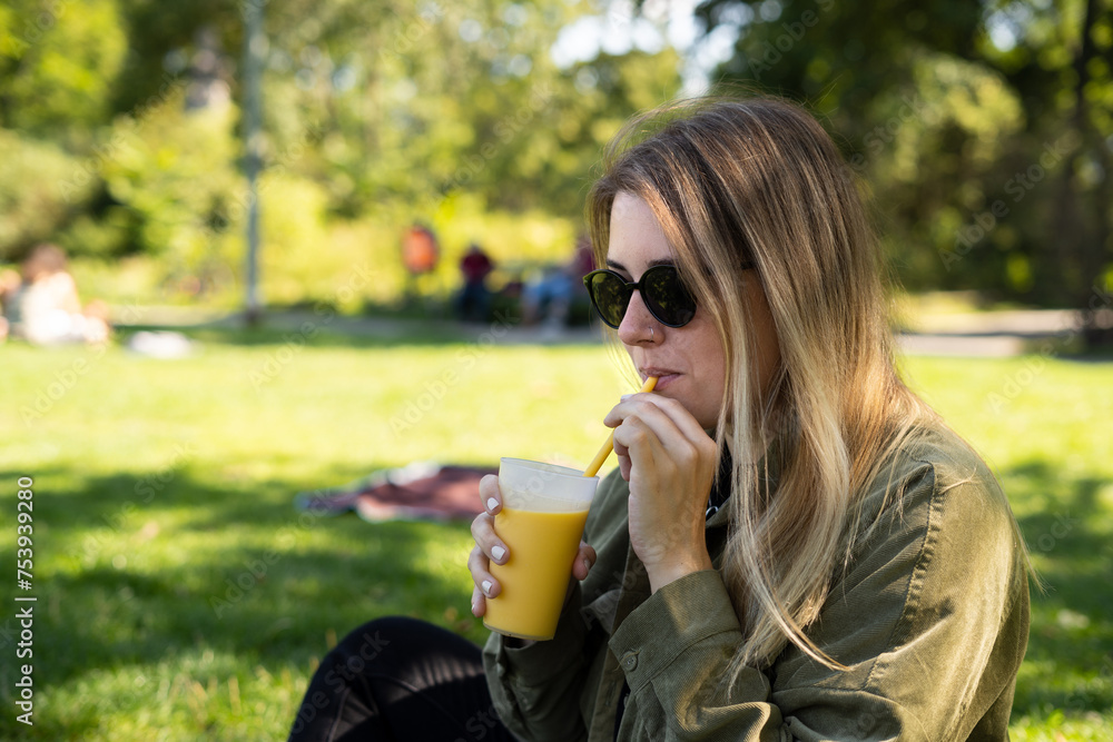 Young smiling beautiful woman drinking juice in the park Young smiling beautiful woman drinking juice in the park