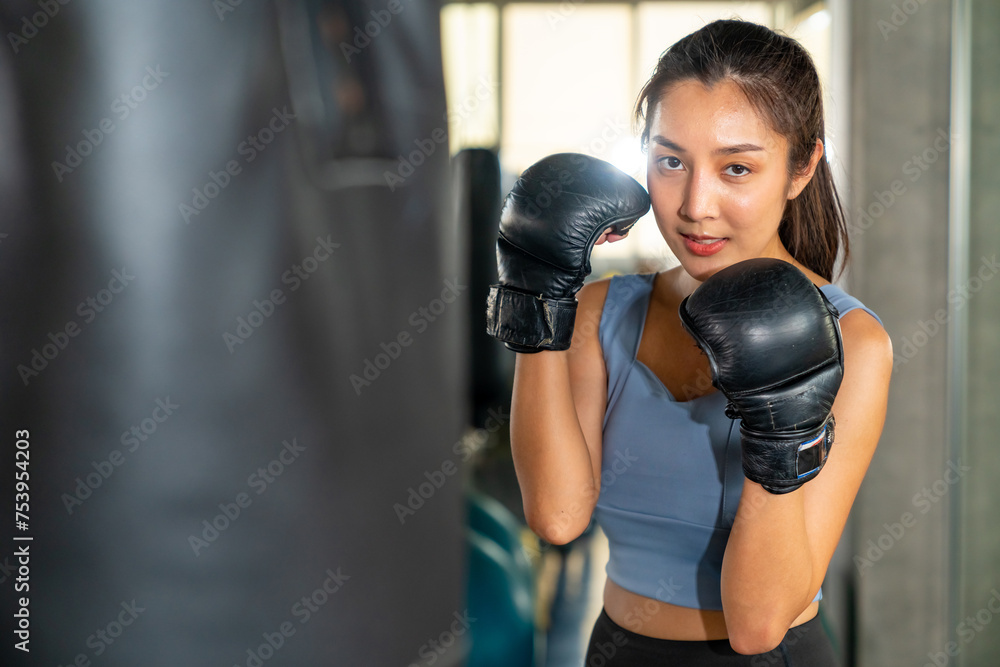 Healthy Asian woman do sport training workout boxing exercise with punching bag at fitness gym. Active sportswoman practicing fighting exercise kickboxing at sport club. Health care motivation concept