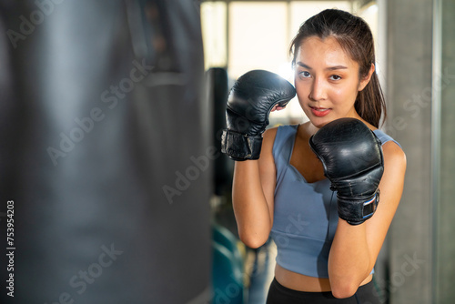 Healthy Asian woman do sport training workout boxing exercise with punching bag at fitness gym. Active sportswoman practicing fighting exercise kickboxing at sport club. Health care motivation concept © CandyRetriever 