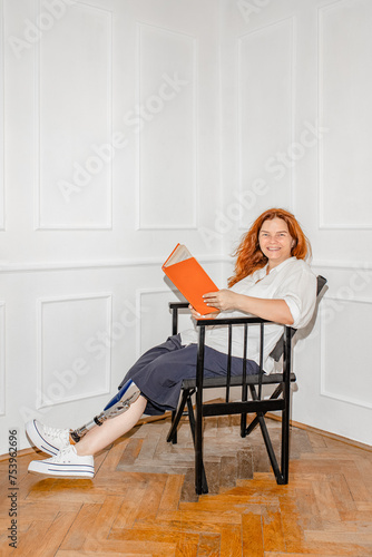 A disabled woman with a prosthetic leg with a book smiles at home
