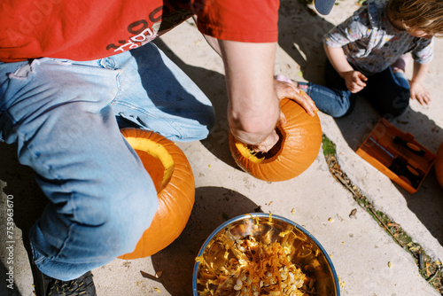 father and toddler child carving messy pumpkin outdoors photo