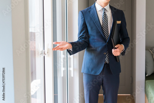 サッシ・窓の説明・案内・提案をするハウスメーカーのスーツ姿の若い男性ビジネスマン 