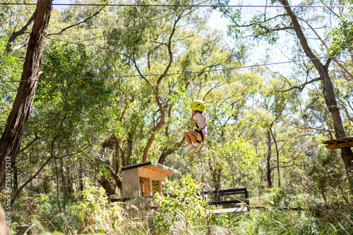 A kid on a zippy line at a tree climbing park. photo