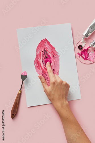 Crop of painter hand drawing female genitalia on canvas photo