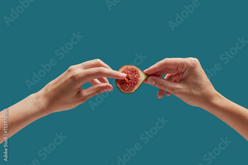 Female hands touching seeds of fresh half fig over blue background photo