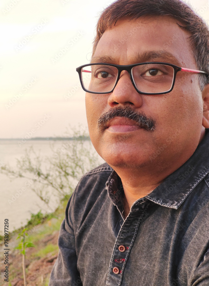 Portrait of an Indian man sitting at the bank of a river Portrait of an Indian man sitting at the bank of a river