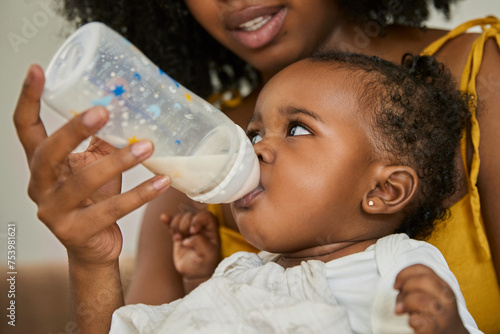 Close-up of a young girl drinking milk from a baby bottle photo