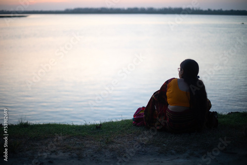Indian woman wearing traditional dress sit at the bank of a river  photo