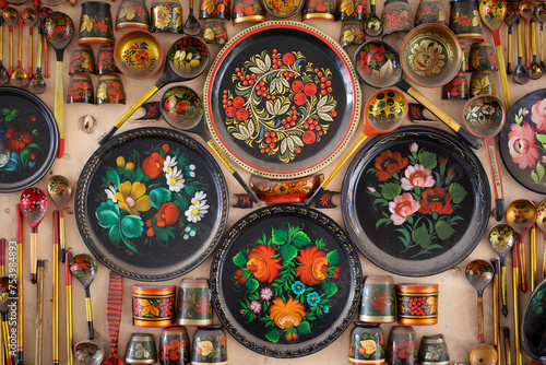 Colorful hand-painted tableware set: plates, cups and spoons on wall