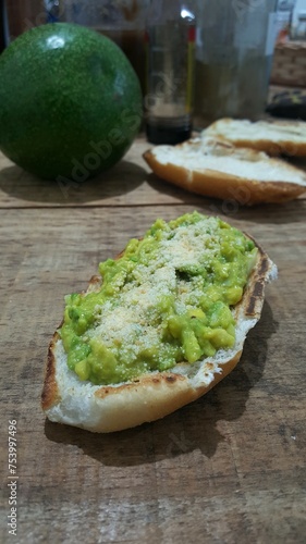 Lanche composto de torrada de pão com guacamole de abacate, sal, limão e queijo. photo