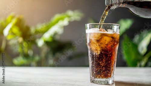 Refreshing carbonated drink poured into tall glass on white table, with blurred background photo