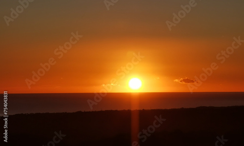 Il Sole accecante che all’alba sorge dal mare visto da sopra le colline 