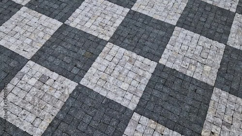 chess board made of small marble cubes. the gray and white mosaic in the square is a classic visual cliché. pavers work advertising spot. surface detail photo