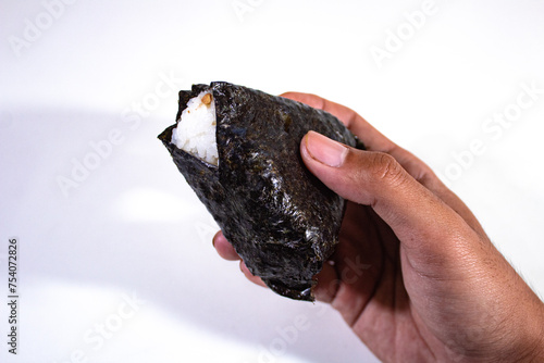 Traditional Japanese food, triangular onigiri stuffed with rice and wrapped in seaweed, then held in the right hand