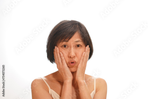顔に手をやる肌に悩むシミ・シワのある中年女性 photo