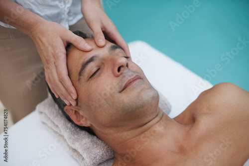 Resort, spa and man relax for massage on table in hotel, calm and care for body in vacation. Holiday, luxury and male person on break for weekend, accommodation and lodge with treatment for skincare