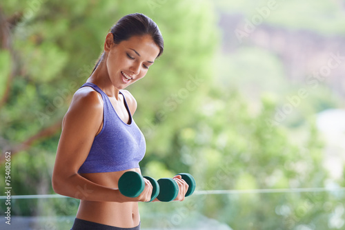 Happy woman, fitness and weightlifting with dumbbells for exercise, workout or muscle gain on balcony. Female person with smile for lifting weight or small barbells for outdoor training on terrace