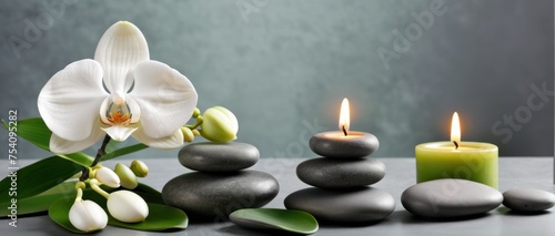 Zen stones  candles  and white orchid on green-grey background.
