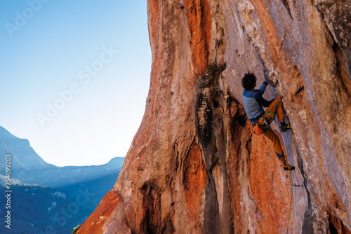 male climber. Athletic man climbing up an overhanging rock with a rope. rock climbing in Turkey.