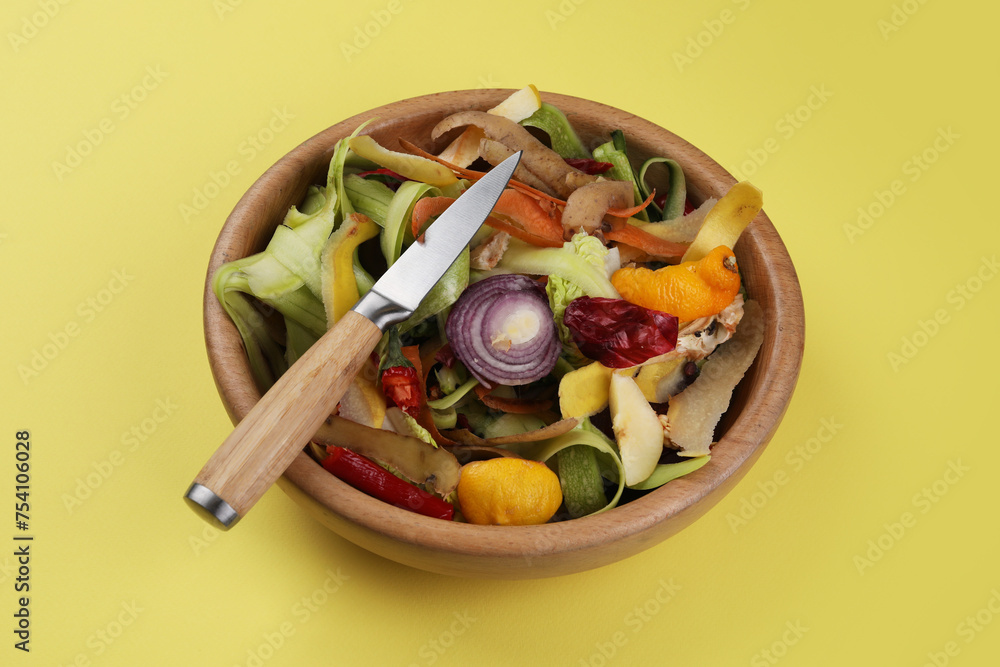 Peels of fresh vegetables and knife on yellow background Peels of fresh vegetables and knife on yellow background