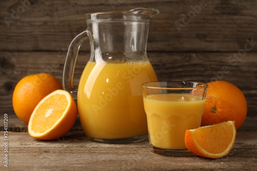 Tasty fresh oranges and juice on wooden table