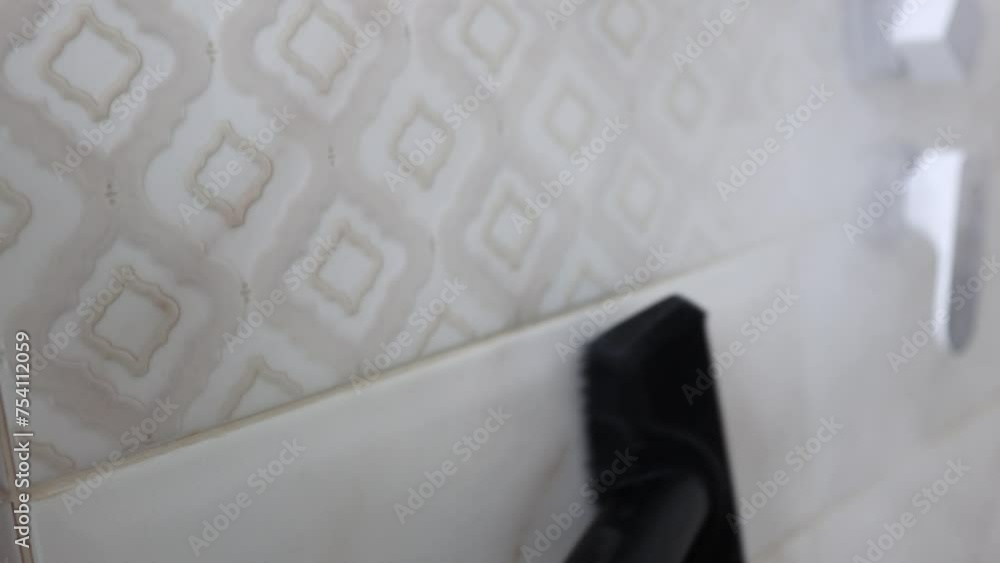 A cleaner in protective gloves washes tiles with a professional steam generator. Cleaning and disinfection in the bathroom with pressurized hot steam A cleaner in protective gloves washes tiles with a professional steam generator. Cleaning and disinfection in the bathroom with pressurized hot steam