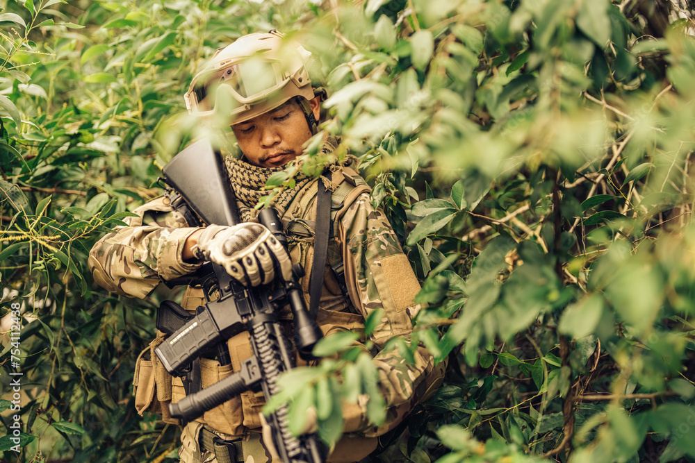 American soldiers camouflage in the bushes from enemies, check the barrels of M16 pistols, wear military uniforms, helmets, vision goggles in a dangerous battlefield from terrorists.