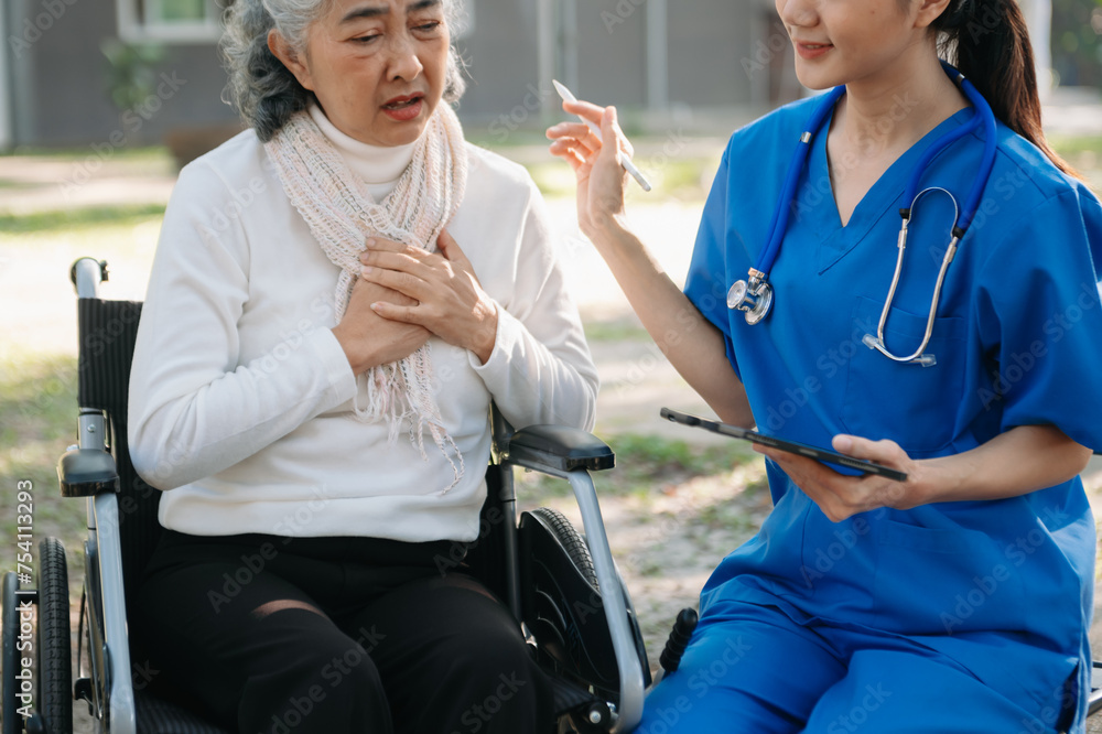 Elderly asian senior woman on wheelchair with Asian careful caregiver and encourage patient, walking in garden. Elderly asian senior woman on wheelchair with Asian careful caregiver and encourage patient, walking in garden.