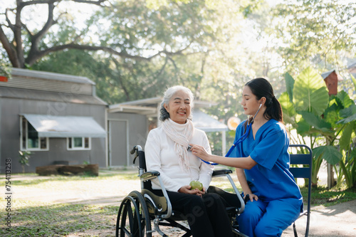 Elderly asian senior woman on wheelchair with Asian careful caregiver. Nursing home hospital